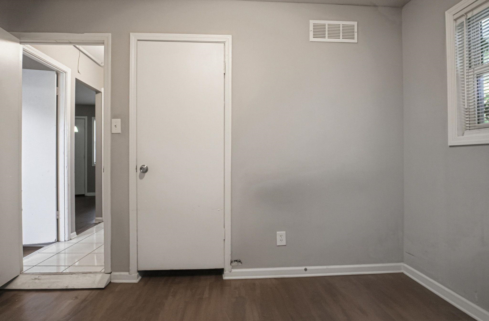 4562 Tulane Road Memphis, TN 38109 - Photo 13 of 32 Light gray wall paint, wood-finish flooring, white window frame, white door, and a white air register