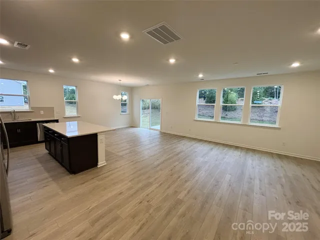 a living room with stainless steel appliances granite countertop furniture wooden floor and a large window