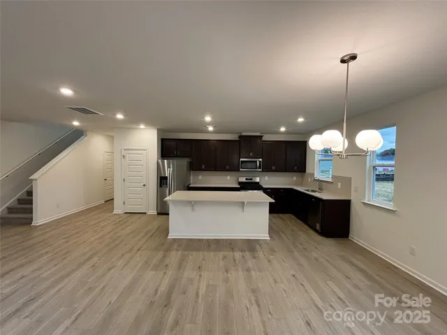 a large kitchen with a white countertops a stove a sink dishwasher with a dining table with wooden floor