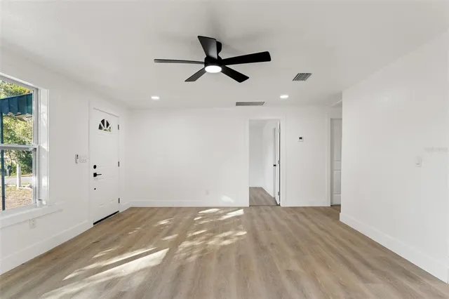a view of empty room with wooden floor and ceiling fan