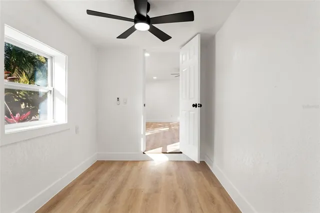 a view of empty room with wooden floor and fan