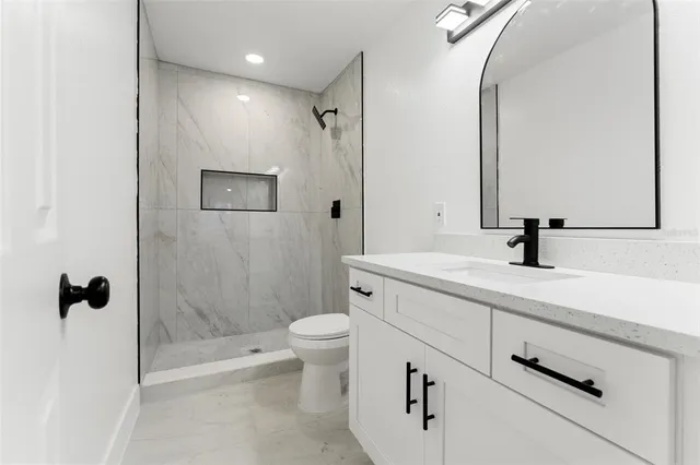 a bathroom with a shower sink vanity and toilet