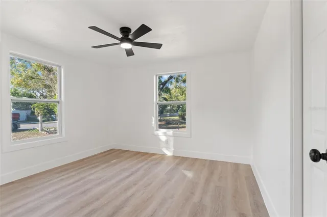 a view of empty room with wooden floor and fan