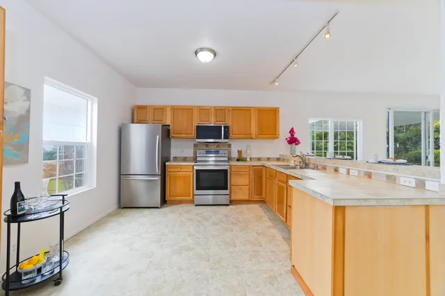 a kitchen with stainless steel appliances a refrigerator a sink a stove a table and chairs