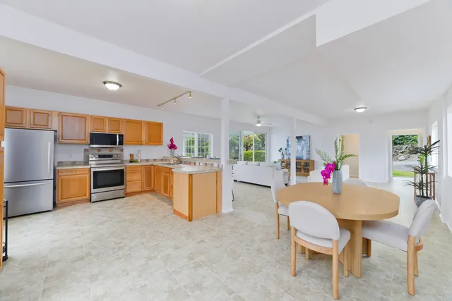 a kitchen with a dining table chairs refrigerator and a sink