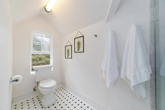 a bathroom with a toilet a sink a shower curtain and a window