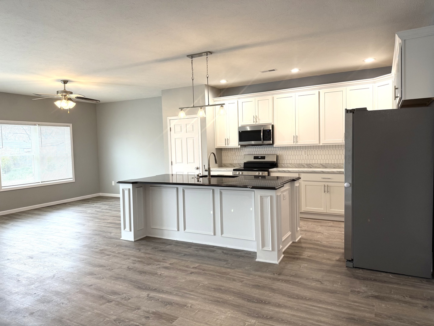 1104 Midway Court Marion, IL 62959 - Photo 4 of 13 a kitchen with kitchen island granite countertop a stove a sink a refrigerator and white cabinets with wooden floor