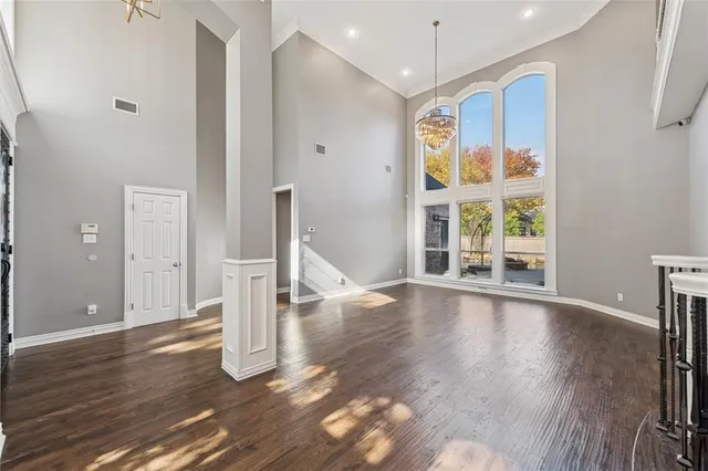 a view of an empty room with wooden floor and fan