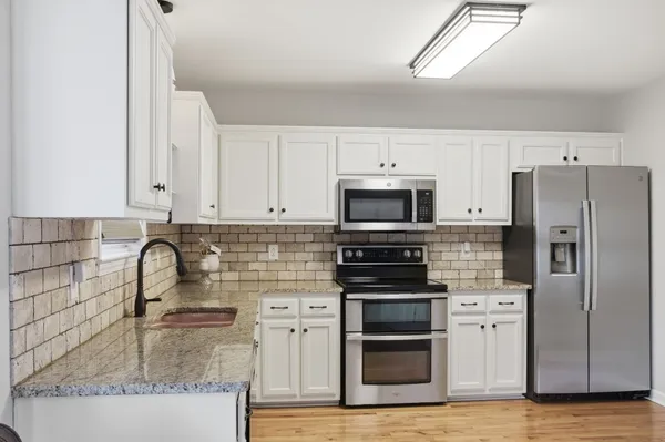 a kitchen with granite countertop a sink stainless steel appliances and cabinets