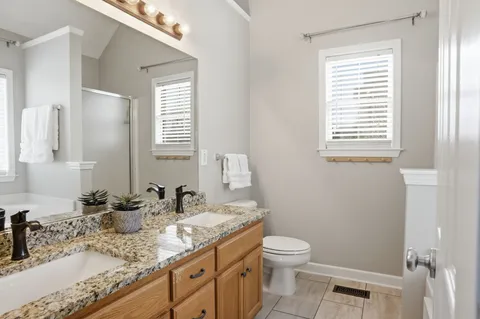 a bathroom with a granite countertop toilet a sink a mirror and a window