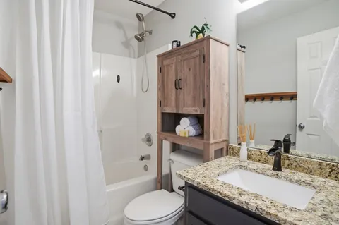 a bathroom with a granite countertop sink toilet and shower