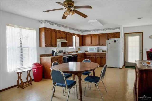 a kitchen with stainless steel appliances granite countertop a stove a refrigerator a microwave oven with a dining table and chairs with wooden floor