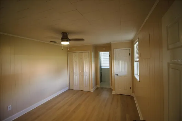 an empty room with wooden floor and a ceiling fan