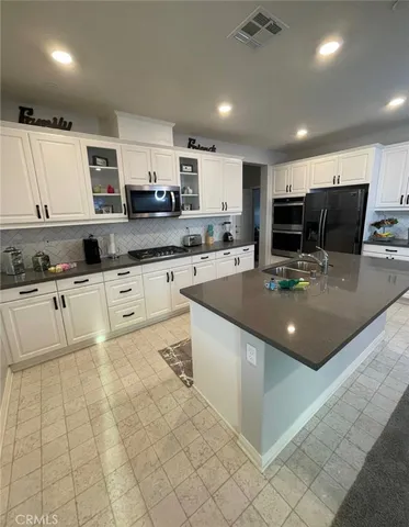 a kitchen with stainless steel appliances granite countertop a sink counter space cabinets and a view of living room