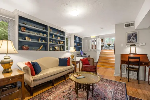 a living room with furniture a bookshelf and a window