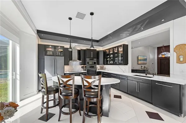 a kitchen with stainless steel appliances a dining table chairs and white cabinets