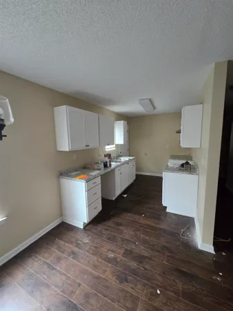 a room with a sink wooden floor and white cabinets