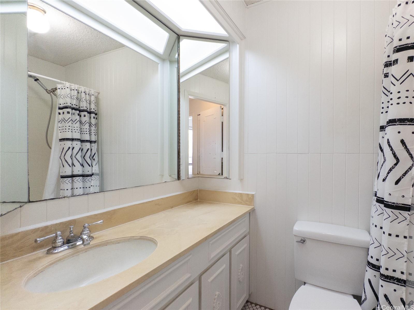 444 Lunalilo Home Road, Unit 506 Honolulu, HI 96825 - Photo 4 of 13 a bathroom with a sink mirror vanity and toilet
