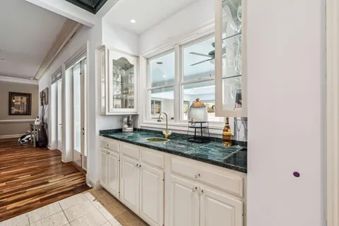 a kitchen with granite countertop a sink and a white wooden cabinets