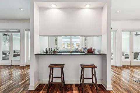 a kitchen with stainless steel appliances granite countertop a table chairs in it and wooden floors