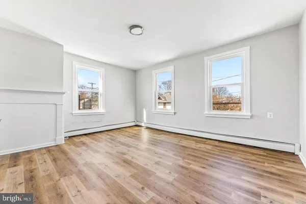 a view of an empty room with window and wooden floor