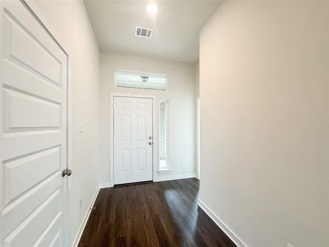 a kitchen with stainless steel appliances kitchen island granite countertop a stove a sink a refrigerator and white cabinets with wooden floor