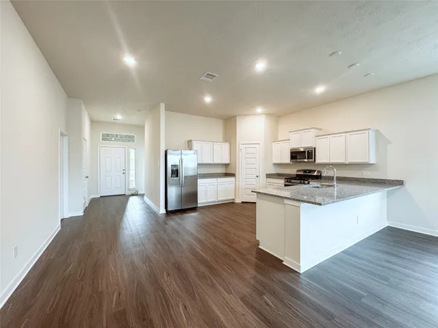 an open kitchen with white cabinets wooden floor and stainless steel appliances