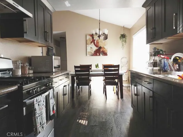 a kitchen with stainless steel appliances granite countertop a stove top oven a sink a dining table and chairs with wooden floor