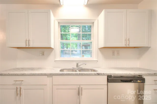 a kitchen with granite countertop white cabinets and a sink