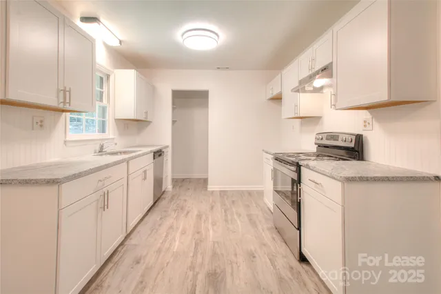 a kitchen with a sink a window a refrigerator and white cabinets