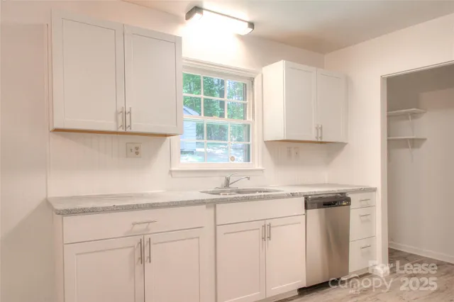 a kitchen with granite countertop white cabinets and a window