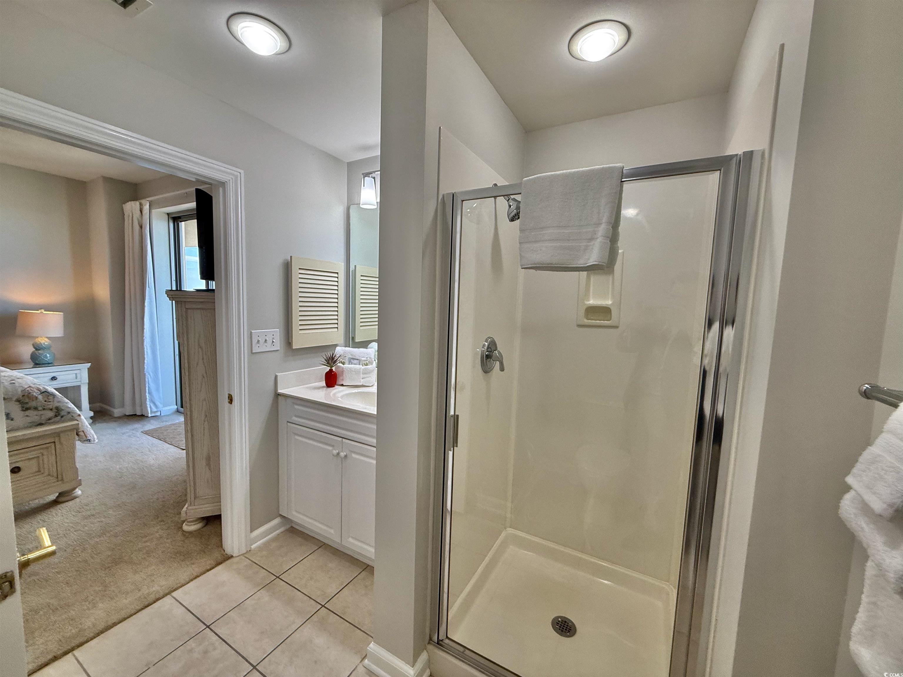8500 Margate Circle, Unit 1108 Myrtle Beach, SC 29572 - Photo 38 of 40 Ensuite bathroom featuring light carpet, a stall shower, vanity, and light tile patterned floors