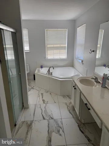 a spacious bathroom with a tub sink and mirror