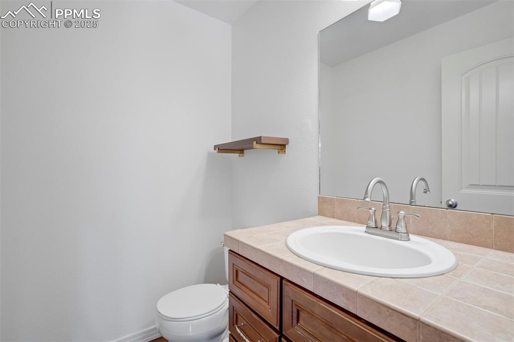 1571 Promontory Bluff View Colorado Springs, CO 80921 - Photo 15 of 49 a bathroom with a granite countertop sink a toilet and a mirror