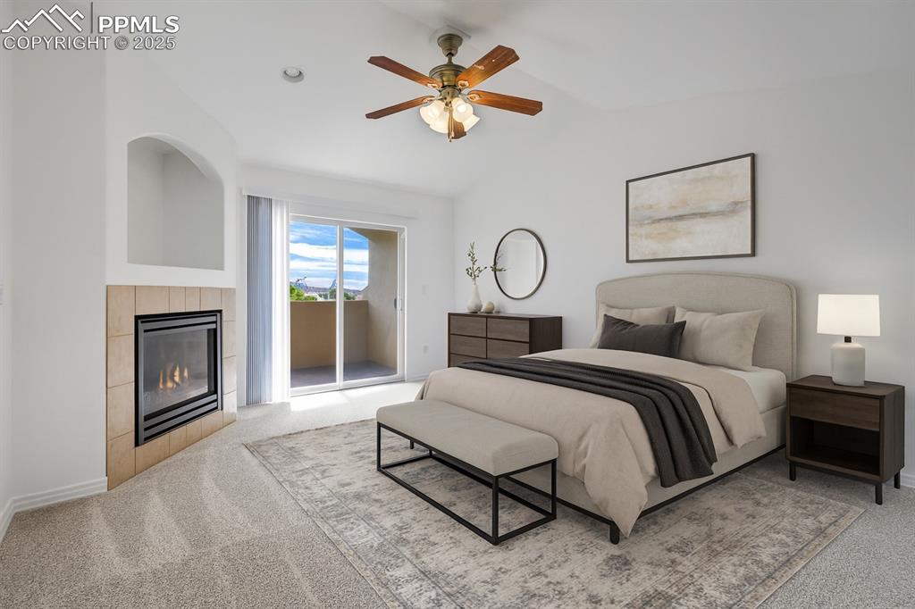 1571 Promontory Bluff View Colorado Springs, CO 80921 - Photo 17 of 50 Bedroom featuring access to exterior, light colored carpet, a tiled fireplace, vaulted ceiling, and ceiling fan