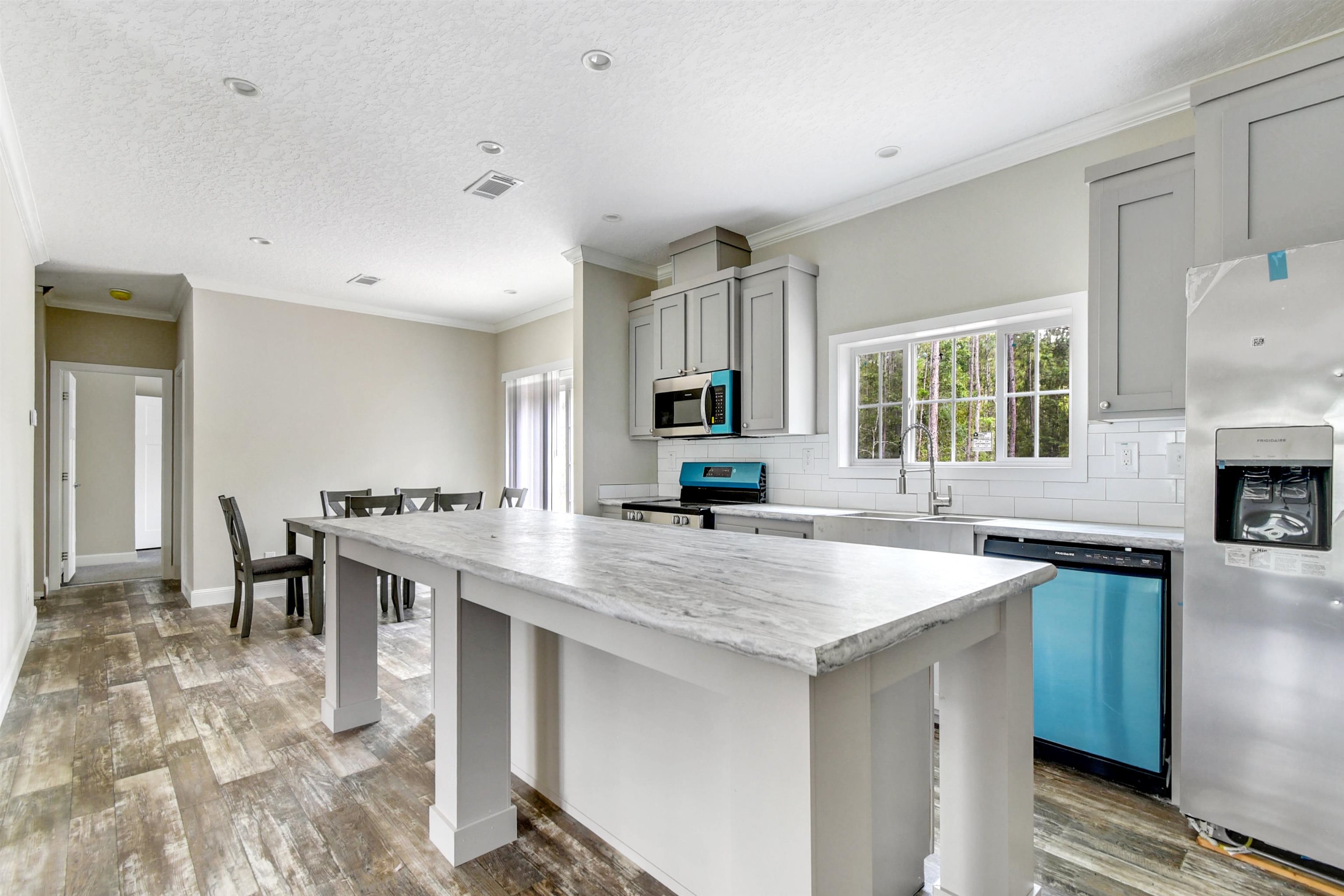 4240 Isaac Street Hastings, FL 32145 - Photo 2 of 19 Kitchen with tasteful backsplash, crown molding, appliances with stainless steel finishes, a center island, and gray cabinets