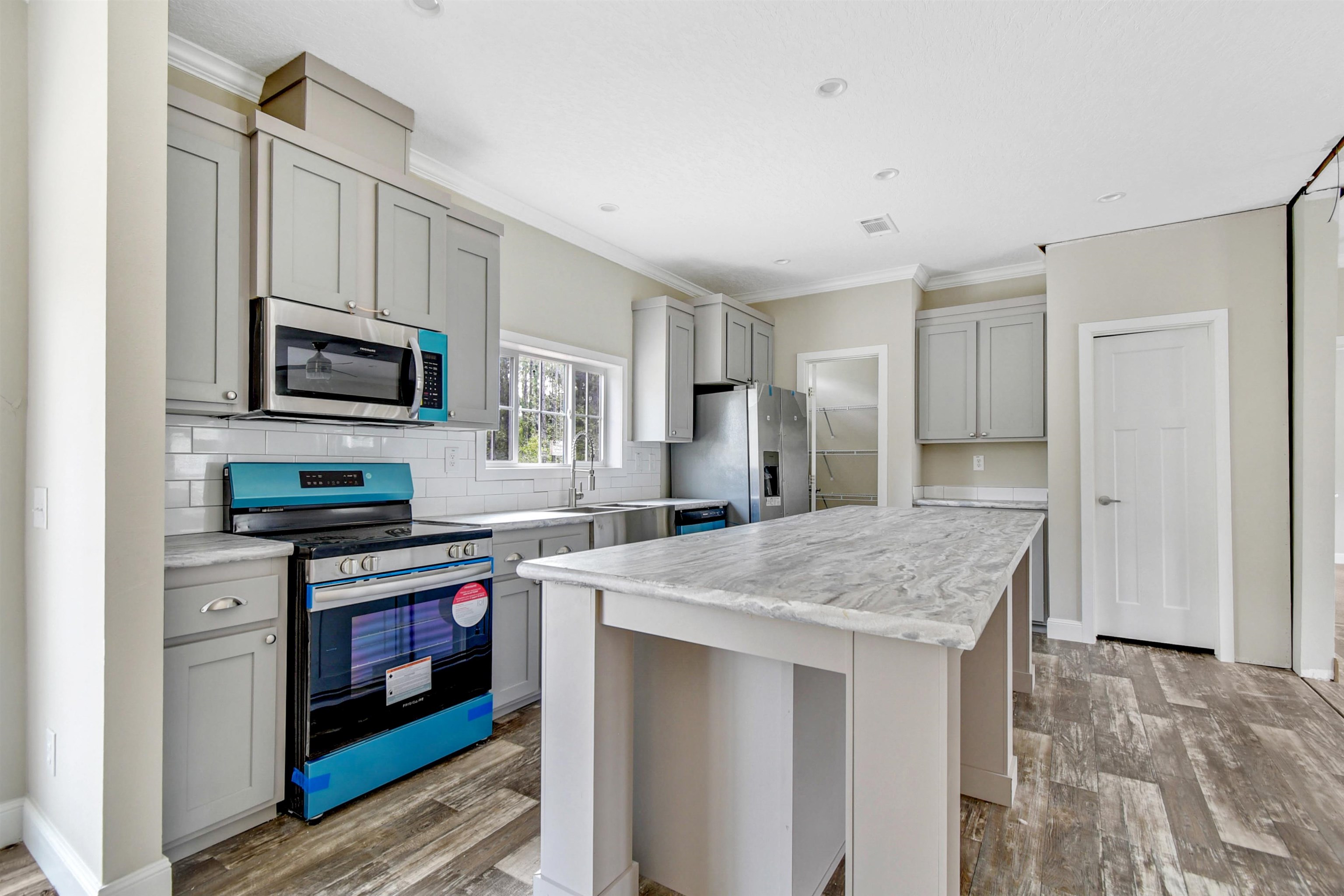 4240 Isaac Street Hastings, FL 32145 - Photo 3 of 19 Kitchen with gray cabinets, appliances with stainless steel finishes, ornamental molding, light countertops, and decorative backsplash