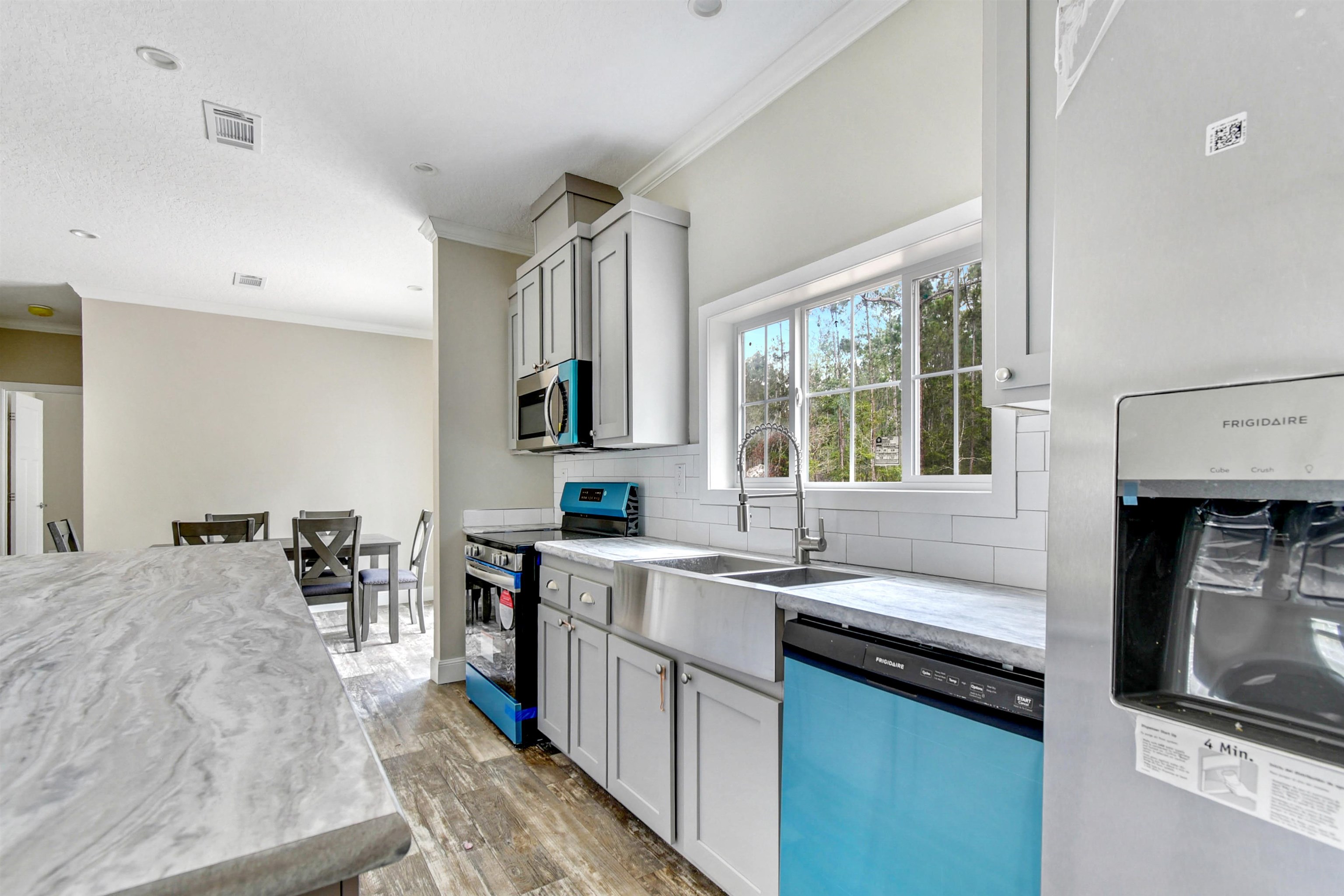 4240 Isaac Street Hastings, FL 32145 - Photo 4 of 19 Kitchen featuring appliances with stainless steel finishes, ornamental molding, backsplash, light wood-style flooring, and light stone counters