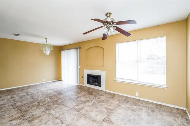 a view of an empty room with chandelier fan and a fireplace