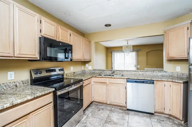 a kitchen with stainless steel appliances granite countertop a sink stove and microwave