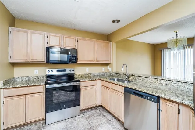 a kitchen with stainless steel appliances granite countertop a sink and dishwasher a stove top oven with white cabinets