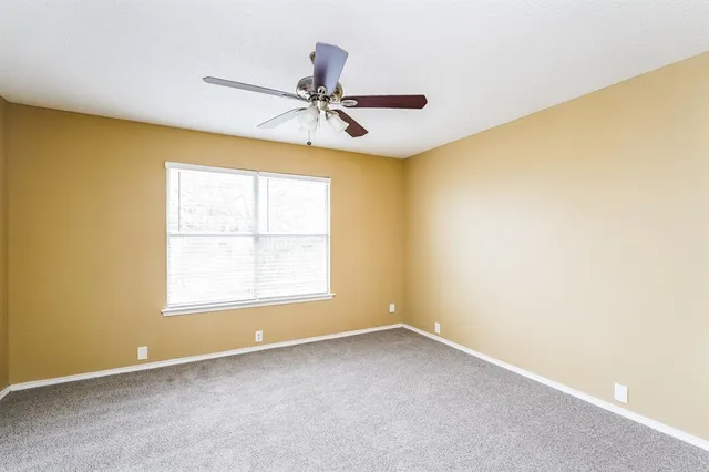 an empty room with a window and a ceiling fan
