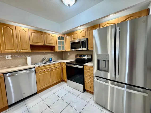 a kitchen with granite countertop a refrigerator stove top oven and sink