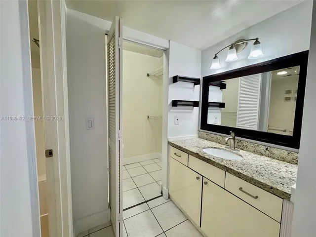 a bathroom with a granite countertop sink a mirror and a shower
