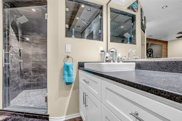 a bathroom with a granite countertop sink a mirror and shower