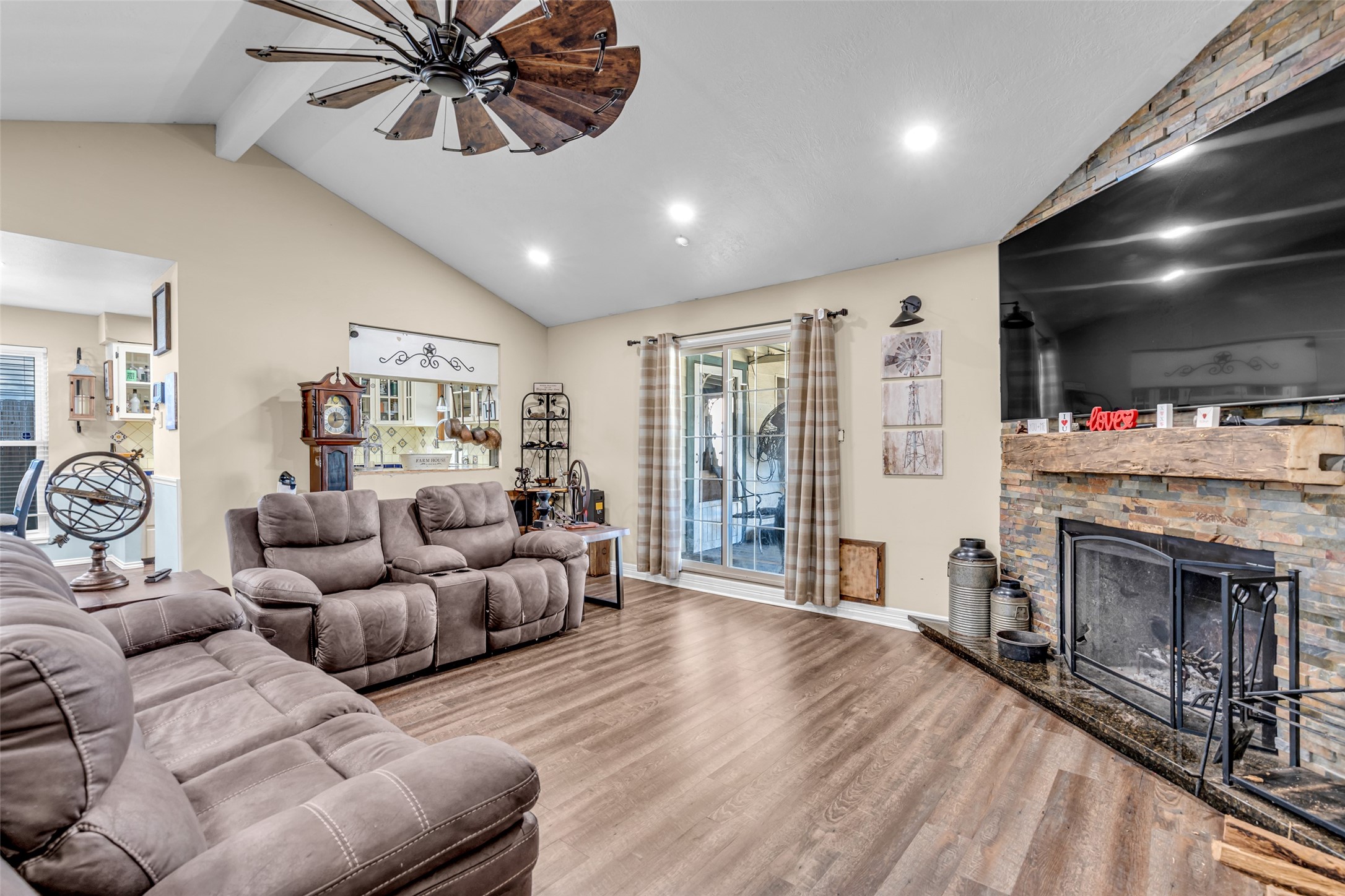 25473 White Oak Lane Splendora, TX 77372 - Photo 2 of 24 Spacious open living room featuring vaulted ceilings, a cozy wood fireplace, and sliding glass doors that open to the patio, creating a perfect entertaining space.