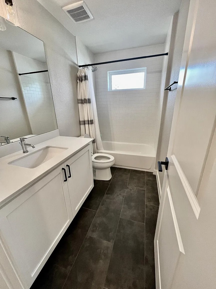 1924 Bunche Road, Unit A Austin, TX 78721 - Photo 11 of 14 Full bathroom featuring shower / bathtub combination with curtain, vanity, a textured wall, and dark tile patterned floors