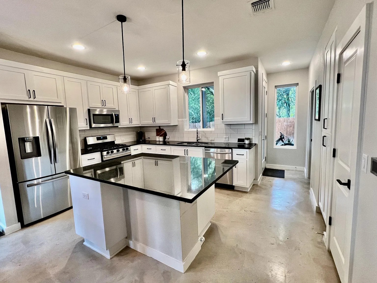 1924 Bunche Road, Unit A Austin, TX 78721 - Photo 5 of 14 Kitchen with a kitchen island, stainless steel appliances, concrete floors, and white cabinetry