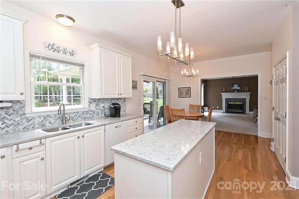 324 Gringley Hill Road Fort Mill, SC 29708 - Photo 11 of 48 a kitchen with center island a sink dishwasher a stove and white cabinets with wooden floor