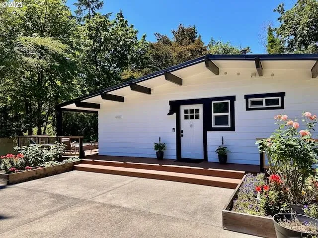 a front view of a house with lots of flowers and trees